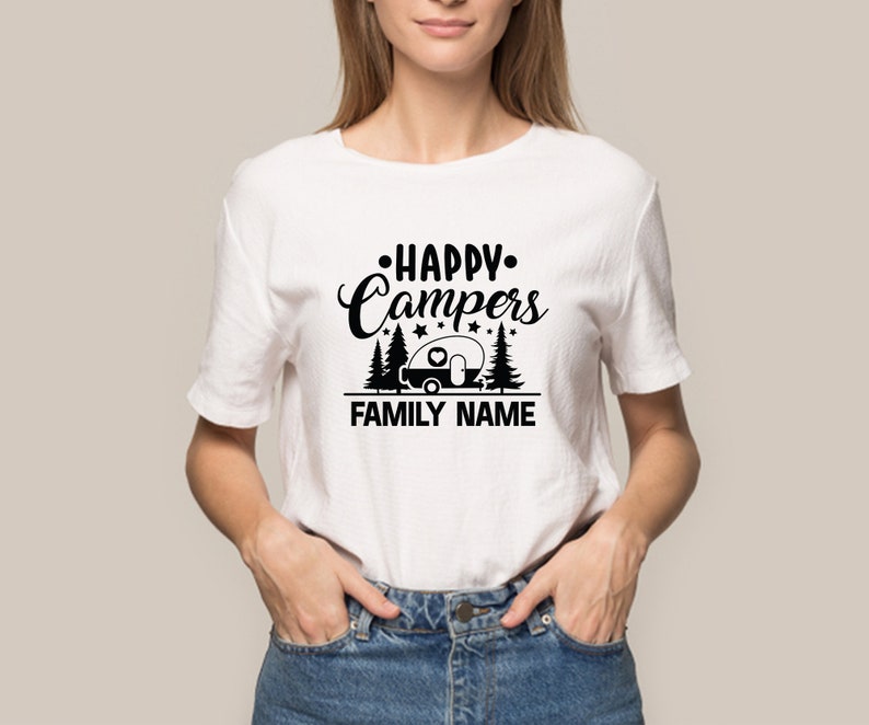 Puede incluir: Camiseta blanca con un dise&ntilde;o gr&aacute;fico negro que dice "Happy Campers" con una caravana y &aacute;rboles. El texto "FAMILY NAME" est&aacute; debajo del gr&aacute;fico.