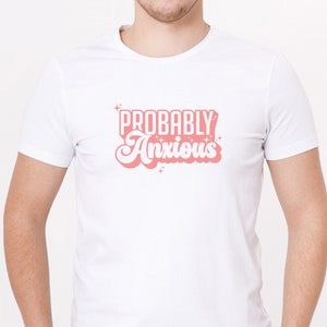 K&ouml;nnte beinhalten: Wei&szlig;es T-Shirt mit einer pinkfarbenen Grafik im Retro-Stil, auf dem "Probably Anxious" steht.