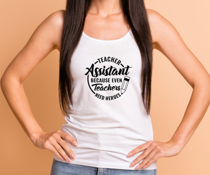 Pu&ograve; includere: Canotta bianca con una grafica circolare nera che dice "Teacher Assistant Because Even Teachers Need Heroes" con un'icona di matita.