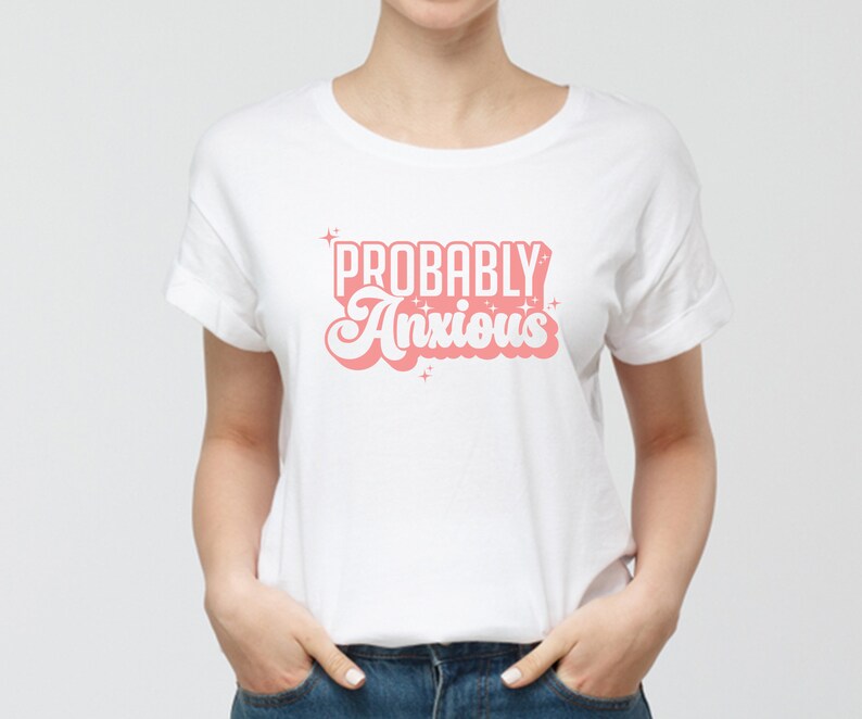 K&ouml;nnte beinhalten: Wei&szlig;es T-Shirt mit dem Text "PROBABLY Anxious" in rosa Retro-Schrift.