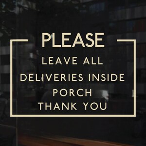A dark-colored sign with beige text that reads: PLEASE LEAVE ALL DELIVERIES INSIDE PORCH THANK YOU. The text is enclosed in a beige rectangular border.