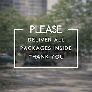 May include: A rectangular white frame containing the text PLEASE DELIVER ALL PACKAGES INSIDE THANK YOU in a clean sans-serif font. The sign is designed to provide clear delivery instructions for couriers and postal workers at a residence.