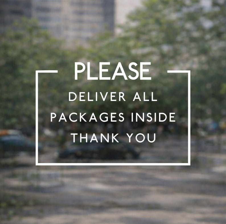 May include: A rectangular white frame containing the text PLEASE DELIVER ALL PACKAGES INSIDE THANK YOU in a clean sans-serif font. The sign is designed to provide clear delivery instructions for couriers and postal workers at a residence.