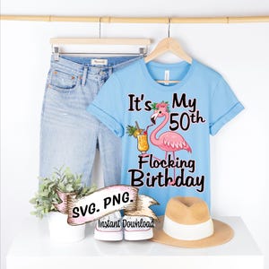 Puede incluir: Una camiseta azul claro con el texto "It's My 50th Flocking Birthday" y un flamenco rosa sosteniendo una bebida tropical. El flamenco tiene una corona de flores en la cabeza. El texto "SVG. PNG. Descarga instantánea" está en una cinta rosa.