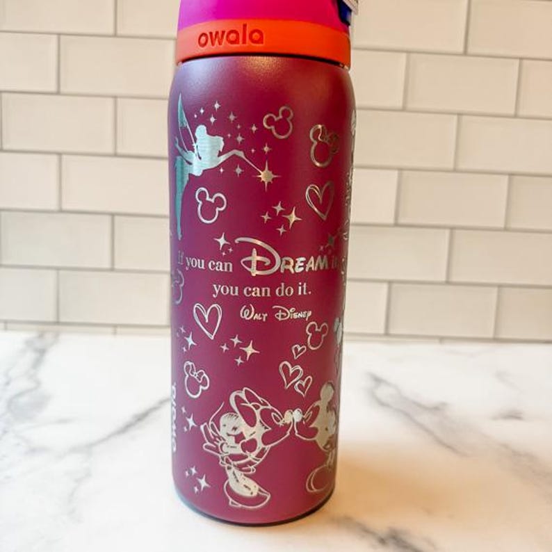 A purple water bottle with Disney-themed designs and a motivational quote on it.