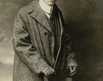 Fotografía antigua de caballero con abrigo, estilo RPPC, de principios del siglo XX, retrato de estudio, en tono sepia.