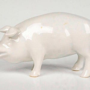 May include: A glossy, off-white ceramic pig figurine. The pig is depicted in a standing position with its head slightly raised and mouth open. The figurine has a smooth, reflective surface and is a decorative item.