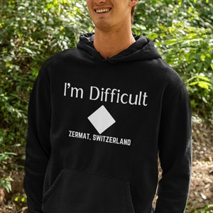 May include: A black hooded sweatshirt with the text "I'm Difficult" and a white diamond symbol with the text "Zermat, Switzerland" below it.