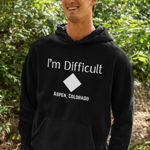 May include: A black hoodie with a white diamond symbol and the text "I'm Difficult" and "Aspen, Colorado".