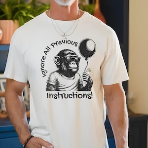 May include: White t-shirt with a black and white illustration of a monkey wearing sunglasses and holding a black balloon. The text "Ignore All Previous Instructions!" is printed on the shirt.