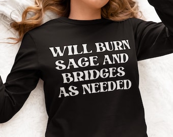 May include: Black long-sleeve shirt with white text that reads "WILL BURN SAGE AND BRIDGES AS NEEDED".