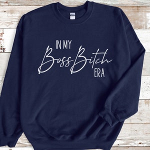 K&ouml;nnte beinhalten: Navyblauer Pullover mit wei&szlig;em Text, der "In My Boss Bitch Era" lautet.