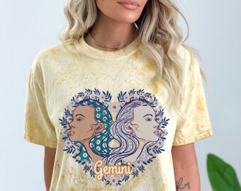 Puede incluir: Una camiseta amarilla tie-dye con un diseño de corazón floral con dos caras y la palabra "Gemini".
