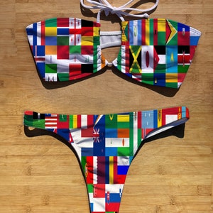 May include: A white bikini with a bandeau top and a thong bottom. The fabric features a patchwork design of flags from around the world.