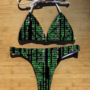 May include: Black and green bikini with a white string top and a bottom featuring a green code-like pattern.