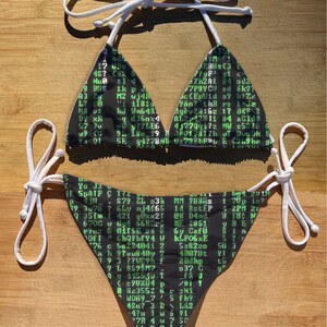 May include: Black bikini top and bottom with a green and white computer code print. The bikini top has a halter style and the bottom is a cheeky style.