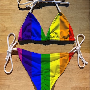 May include: A rainbow striped bikini with white ties. The top is a triangle style and the bottom is a cheeky cut.