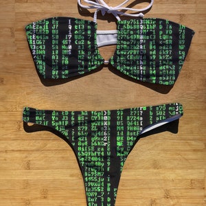 May include: Black and green bikini top and bottom with a computer code pattern. The top has a white halter strap and a cut-out design in the front. The bottom is a thong style.