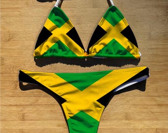 May include: A two-piece bikini set featuring the Jamaican flag design. The top is a triangle style with white straps, and the bottom is a thong cut. The colors include green, yellow, and black.