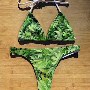 Può includere: Bikini verde con stampa a foglia di marijuana. La parte superiore è di stile triangolare con spalline regolabili. La parte inferiore è di stile tanga.