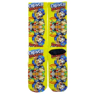 May include: A pair of yellow, blue, and red socks with a repeated pattern of a cartoon pirate holding a bowl of cereal. The cereal box says "Cap'n Crunch's Crunch Berries".