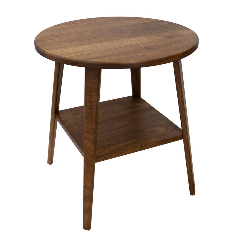 K&ouml;nnte beinhalten: Ein runder Holz-Beistelltisch mit einem unteren Regal. Der Tisch hat eine dunkelbraune Holzoptik und abgeschr&auml;gte Beine.