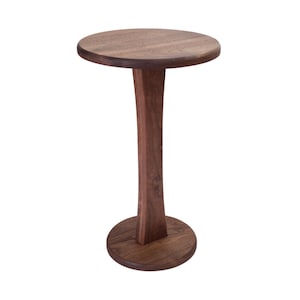 May include: A small, round wooden side table with a dark brown finish. The table has a circular top, a slender, curved central support, and a circular base. The table is approximately 24 inches tall.