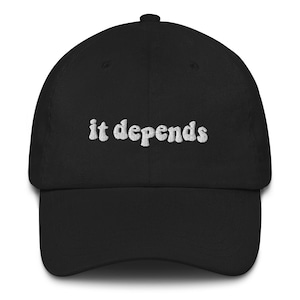 May include: A black baseball cap with white embroidered text that reads "it depends".