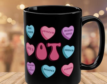 May include: Black coffee mug with a white design of pink and blue hearts with text that says "OT" in the centre. The hearts have text on them such as "Advocate", "Independence", "Strength", "Mobility", "Balance", "ADL's", "Fine Motor", "Movement is Medicine".