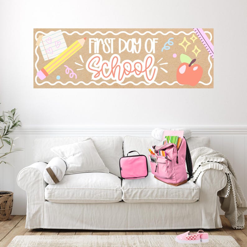 K&ouml;nnte beinhalten: Ein rechteckiges Banner mit beigem Hintergrund und dem Text First Day of School in wei&szlig;er und rosa Schreibschrift. Das Design enth&auml;lt Illustrationen eines gelben Bleistifts, eines Notizbuchs mit Herzen, eines roten Apfels und eines rosa Lineals.
