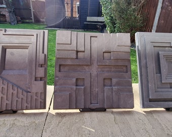 May include: Three square concrete tiles with different geometric patterns. The tiles are gray and brown and have a textured surface.