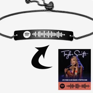 Puede incluir: Pulsera negra con código Spotify y placa rectangular. La pulsera está conectada a una cadena negra. La imagen también muestra la portada de un álbum de Taylor Swift con un código Spotify en la parte inferior.