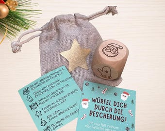 May include: A light brown fabric drawstring pouch with a gold star, a wooden die featuring a Santa and mitten icon, and two light blue instruction cards with German text including "WÜRFEL DICH DURCH DIE BESCHERUNG" and icons.
