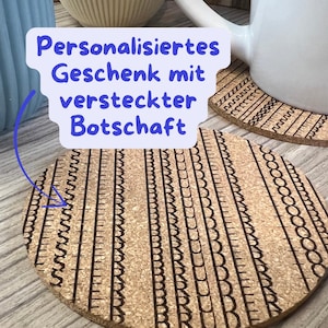 Könnte beinhalten: Runde Untersetzer aus Kork mit einem geätzten Design. Die Untersetzer haben einen hellbraunen Hintergrund mit dunkelbraunen geätzten Mustern. Der Text "Personalisiertes Geschenk mit versteckter Botschaft" befindet sich in einer blauen Sprechblase.
