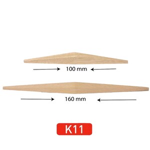 May include: Two wooden dowels, one 100 mm long and the other 160 mm long. The dowels are tapered at the ends. The dowels are labeled "K11".