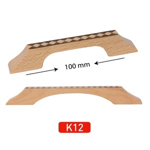 May include: A wooden cabinet door pull with a checkered inlay design. The pull is 100 mm wide. The pull is labeled K12.