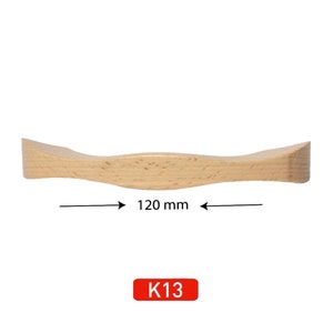 May include: A light wood cabinet door pull with a curved design. The pull is 120 mm wide and labeled K13.