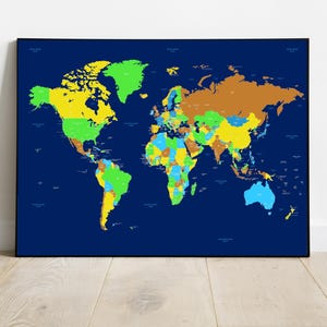 May include: A framed world map with a dark blue background. The continents are colored in shades of yellow, green, brown, and blue, with country borders clearly defined. The map is displayed against a white wall and a wooden floor.