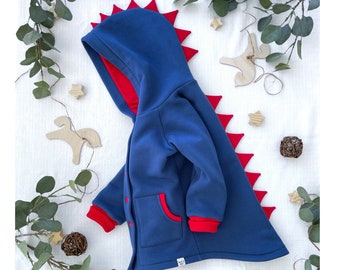 May include: A blue hooded sweatshirt with a red dinosaur tail design. The sweatshirt has a red zipper and a red pocket on the front.