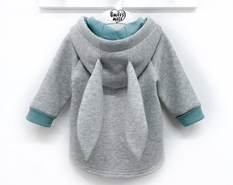 May include: Gray hooded sweatshirt with long sleeves and teal trim. The back of the sweatshirt has two large bunny ears.