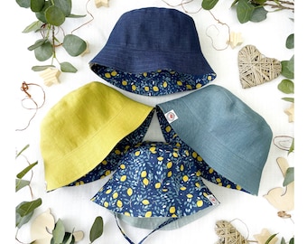 May include: Four reversible bucket hats. Two hats are blue with a lemon print on the inside. One hat is yellow with a lemon print on the inside. One hat is teal with a lemon print on the inside.