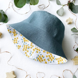 May include: A teal blue bucket hat with a white and yellow floral print lining. The hat is made of a soft, linen fabric.