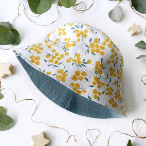 May include: A white bucket hat with a yellow floral pattern. The hat has a teal blue underside.