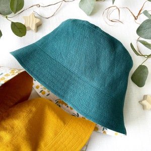 May include: A teal linen bucket hat with a yellow and white floral print lining.