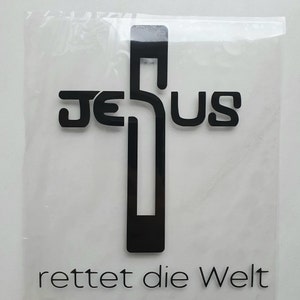 Könnte beinhalten: Schwarze Grafik eines Kreuzes mit dem Wort "JESUS" in das Design integriert. Unter dem Kreuz sind die Worte "rettet die Welt" in Schwarz gedruckt. Das Bild befindet sich auf weißem Hintergrund.