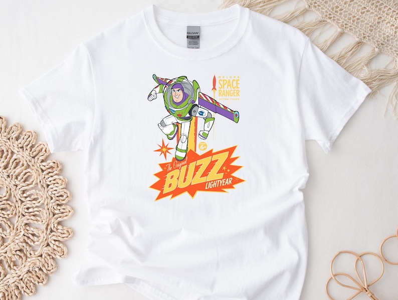 Puede incluir: Camiseta blanca con un gr&aacute;fico colorido de Buzz Lightyear. El dise&ntilde;o incluye el texto "The Original BUZZ LIGHTYEAR" en amarillo y naranja, con "SPACE RANGER" arriba. La camiseta est&aacute; hecha de un material suave y c&oacute;modo.