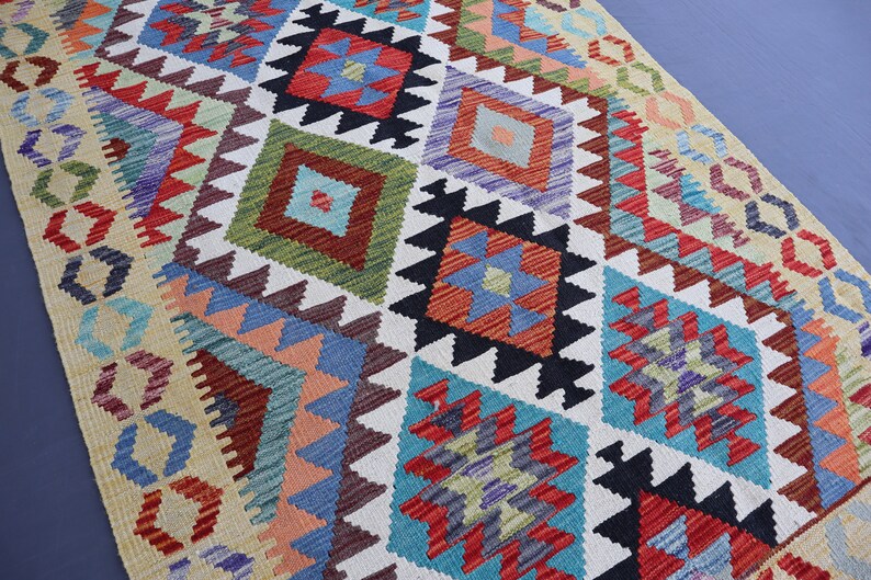 May include: A colorful rug with a geometric pattern in shades of red, blue, green, and white. The rug has a traditional design with intricate details.