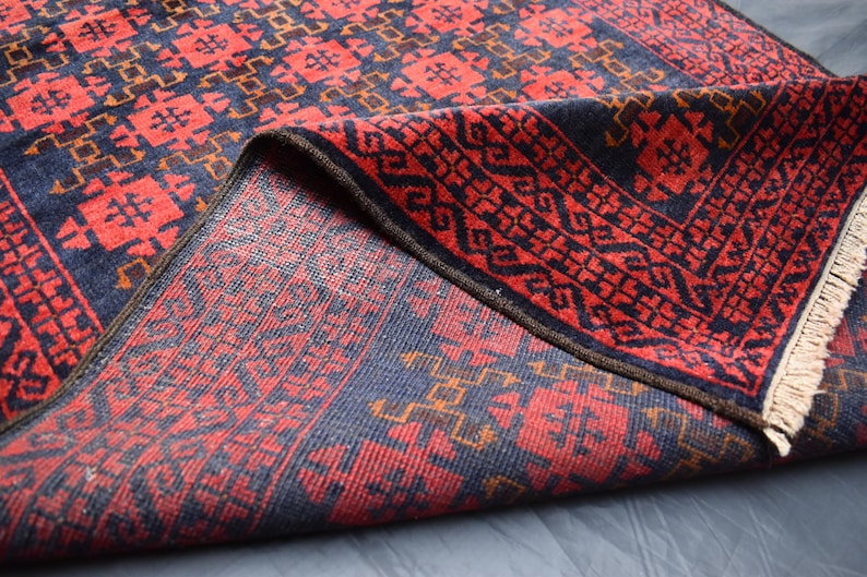 May include: A red and blue patterned rug with a fringe border. The rug is folded in half, showing the intricate design on both sides.