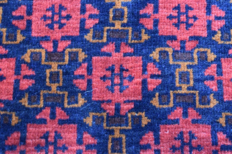 May include: A close-up of a blue and red patterned rug with a geometric design. The rug has a traditional look and is made of woven fibers.