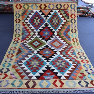 May include: A colorful rug with a geometric pattern in shades of red, blue, green, yellow, and white. The rug has a fringe border and is folded in half.